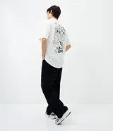 Remera de algodón blanca de corte relajado, con cuello redondo, manga corta y estampa frontal de los Hermanos Metralla.