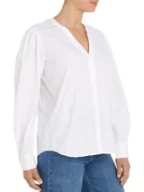 Blusa blanca de algodón orgánico con cuello en V, mangas largas abullonadas con puños abotonados y detalles de encaje vertical.