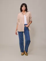 Camisa color beige de algodón y lino, con cuello clásico, cierre frontal con botones, mangas largas con puños abotonados, dos bolsillos con solapa en el pecho y corte holgado.