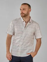 Camisa de manga corta con cuello camisero y botones frontales. El tejido es de color crema con un patrón de cuadros pequeños en negro y marrón.