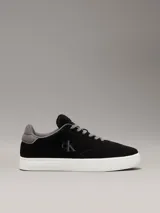 Zapatillas urbanas Calvin Klein Jeans de ante negro con logo CK grabado en el lateral, detalle de talón en gris, cordones grises y suela cupsole blanca.
