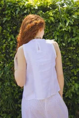 Blusa musculosa blanca de lino con volado diagonal en el frente.