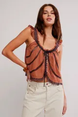 Musculosa color terracota con detalles de encaje oscuro en los bordes y costuras, escote redondo con lazo y cierre frontal con pequeños botones. Presenta tirantes anchos con volados.