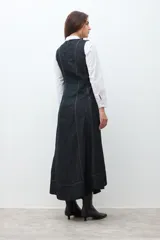 Maxi vestido sin mangas de denim oscuro, con corte al cuerpo en el torso y falda acampanada que cae hasta el tobillo. Presenta costuras visibles en contraste que definen los paneles del vestido.