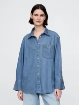 Camisa de jean de corte holgado, con cuello clásico, cierre frontal de botones y bolsillo en el pecho con logo bordado. Presenta mangas largas con puños anchos.
