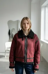 Campera tipo gamulán color bordó con interior y cuello de corderito negro. Presenta detalles de cuero sintético negro en los bordes, cierre frontal metálico y ajuste en el cuello.