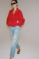 Jeans de tiro medio y corte bootcut cropped de Zara Woman Collection. Confeccionados en denim de efecto lavado en color celeste, presentan diseño de cinco bolsillos, trabillas para cinto, detalle de rotura en la rodilla izquierda y bajo evasé sin costuras. Cierre frontal con cremallera y botón metálico.