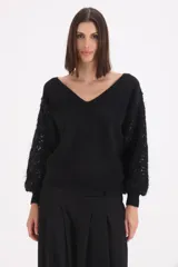 Sweater negro de punto con escote en V y mangas largas abullonadas con bordados de lentejuelas al tono.
