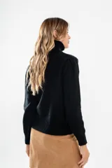 Polera de tejido de punto color negro, con cuello tortuga alto y puños y ruedo acanalados.