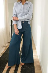 Pantalon de jean azul oscuro con corte wide leg, tiro medio y costuras frontales verticales. Presenta cierre frontal con botón a la vista.