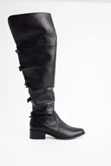 Bota bucanera de cuero vacuno color negro, con caña alta y detalle de lazos decorativos en la parte posterior. Cuenta con taco bajo cuadrado y punta redondeada.