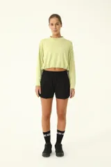 Buzo crop color verde claro, con cuello redondo y mangas largas holgadas. Presenta frunce en el ruedo mediante cordón elástico y tanca.