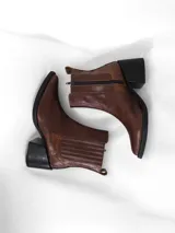 Bota de cuero color marrón con caña corta, taco cuadrado y cierre interno.