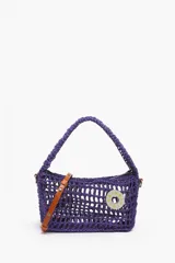 Bolso de mano tejido color violeta con asa corta y correa de cuero marrón extraíble.