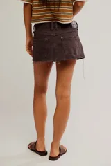 Minifalda de denim rígido marrón, de tiro bajo y calce relajado, con diseño de cinco bolsillos, cierre de botones y ruedo desmechado.