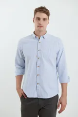 Camisa de manga larga con estampado de rayas verticales en tonos azul y blanco. Presenta cuello button-down, cierre frontal con botones de madera y un bolsillo en el pecho con detalle de etiqueta pequeña.