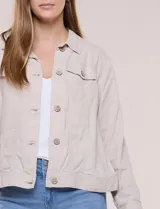 Camperita liviana de silueta recta y calce relajado de lino color beige, con cuello camisero, cartera frontal con botones símil madera y bolsillos aplicados con solapa en el pecho. Presenta mangas largas con puños de cierre abotonado y costuras reforzadas a tono.