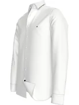 Camisa blanca de corte regular Tommy Hilfiger, confeccionada en algodón dobby Oxford. Tiene cuello con botones, cierre con botones, puños redondeados con dos botones, botón final a contraste y logo de Tommy Hilfiger bordado en el pecho.