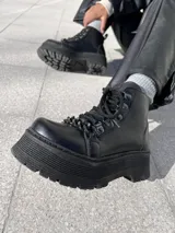 Botas negras de ecocuero con detalle de cadena en la parte delantera y taco de 6cm.