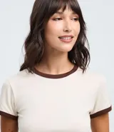 Blusa estilo baby tee color marrón, con cuello redondo y bordes de las mangas en color crema contrastante. Presenta un corte ajustado y manga corta.