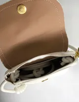 Cartera tipo bandolera de color blanco con textura granulada, solapa con cierre de botón magnético y correa trenzada ajustable mediante nudos.