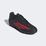 Championes de fútbol Adidas F50 Club para pasto artificial, color negro con detalles en rojo. Presentan exterior sintético Fiberskin con líneas 3D para un mejor toque de pelota y tecnología Sprintgrid. Suela de caucho diseñada para brindar agarre en giros y cortes rápidos.