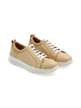 Sneaker de cuero color beige, con suela elevada y estriada de goma blanca, cordones blancos y detalle fruncido elástico en la zona del tobillo.