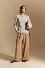 Top de manga larga con textura suave y leve brillo. Presenta una silueta al cuerpo, tajos laterales y terminaciones onduladas en el ruedo.