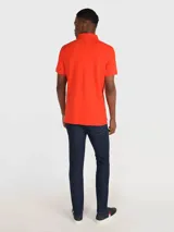 Chomba naranja de Tommy Hilfiger, corte regular, con cuello tipo chomba, cartera de dos botones, logo de la marca bordado en el pecho y mangas cortas.