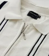 Camisa polo de punto color crema con rayas verticales azul marino, cierre de cremallera, cuello polo y mangas cortas con ribete a juego. Corte slim fit.