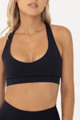 Top deportivo de sujeción media, confeccionado en poliamida y elastano. Presenta un diseño con escote redondo, breteles finos y banda elástica en la cintura para mayor ajuste y soporte. Cuenta con doble tela interna para mayor seguridad durante el entrenamiento.