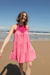 Vestido corto rosado con escote halter de crochet y falda escalonada.