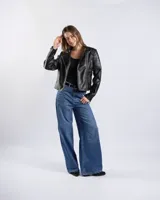 Campera estilo motero de símil cuero color negro, con cuello alto, cierre frontal asimétrico, bolsillos con cierre y detalles acolchados en los hombros.