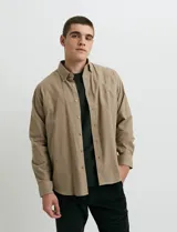 Camisa de franela lisa con cuello button-down, manga larga, botones al tono y bolsillo frontal en el pecho.