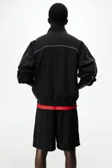 Short de futbol negro de malla, con cintura elástica y cordón ajustable. Cuenta con ribetes blancos en los laterales, bolsillos y el logo de Lotto estampado en blanco en la pierna izquierda.