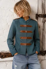 Chaqueta verde estilo militar, de manga larga y cuello mao, con tiras horizontales de cuero marrón en el frente y hombreras decoradas con botones metálicos dorados.