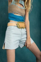 Top corto tejido de punto a crochet, sin mangas, con diseño multicolor en celeste, beige y azul, y aberturas frontales estratégicas tipo cut-out.