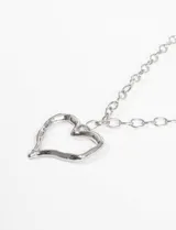 Collar con cadena de eslabones gruesos plateados y un dije de corazón calado con textura irregular y acabado envejecido.