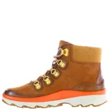 Botas de caña media Caterpillar modelo Tori, confeccionadas en gamuza marrón con detalles en cuero liso. Presentan cordones bicolores, ganchos metálicos dorados, cuello acolchado textil y una suela de plataforma con franja naranja vibrante y base blanca.