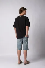 Remera negra de corte oversize con cuello redondo y mangas cortas. Presenta la palabra "simplify" bordada en el pecho en el mismo tono. Confeccionada en tejido de punto con textura sutil tipo waffle.