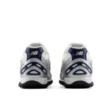 Championes New Balance modelo 204, color plateado y blanco con detalles en azul marino, confeccionados con base de malla transpirable y superposiciones sintéticas, con el logo 'N' característico en los laterales.