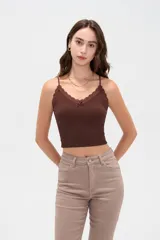Musculosa crop de morley negro con tirantes finos, escote en V decorado con detalles de encaje y un pequeño lazo en el centro.