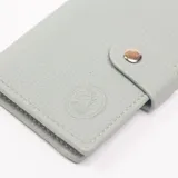 Tarjetero celeste de cuero sintético con cierre de broche metálico.