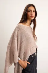 Poncho de lino tejido color tostado, con diseño asimétrico de punto abierto y mangas amplias.