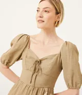 Vestido midi de lino color beige con estampado de follaje blanco, escote corazón con lazo, mangas 3/4 abullonadas y lastex en la espalda.