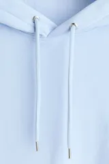Canguro con capucha de H&M, color celeste, confeccionado en mezcla de algodón con interior cepillado. Presenta hombros caídos, cordón de ajuste en la capucha, bolsillo frontal tipo canguro y puños y bajo acanalados.