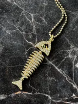Collar compuesto por una cadena fina de plata 925 con baño de oro 18k y un dije en forma de espina de pescado decorado con mini circonias.