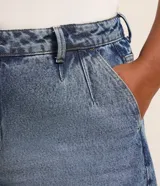 Bermuda de jean tiro alto con pinzas delanteras, bolsillos laterales tipo chino y dobladillo ancho en las perneras.