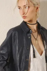 Camisa de cuero ovino color negro, de calce holgado y terminación arrugada. Tiene snaps metálicos color plata vieja con logo de la marca grabada.