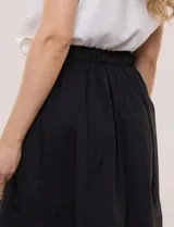 Falda midi evasé de algodón color negro, con tiro alto, pretina con elástico posterior, abotonadura frontal con botones carey y bolsillos laterales.